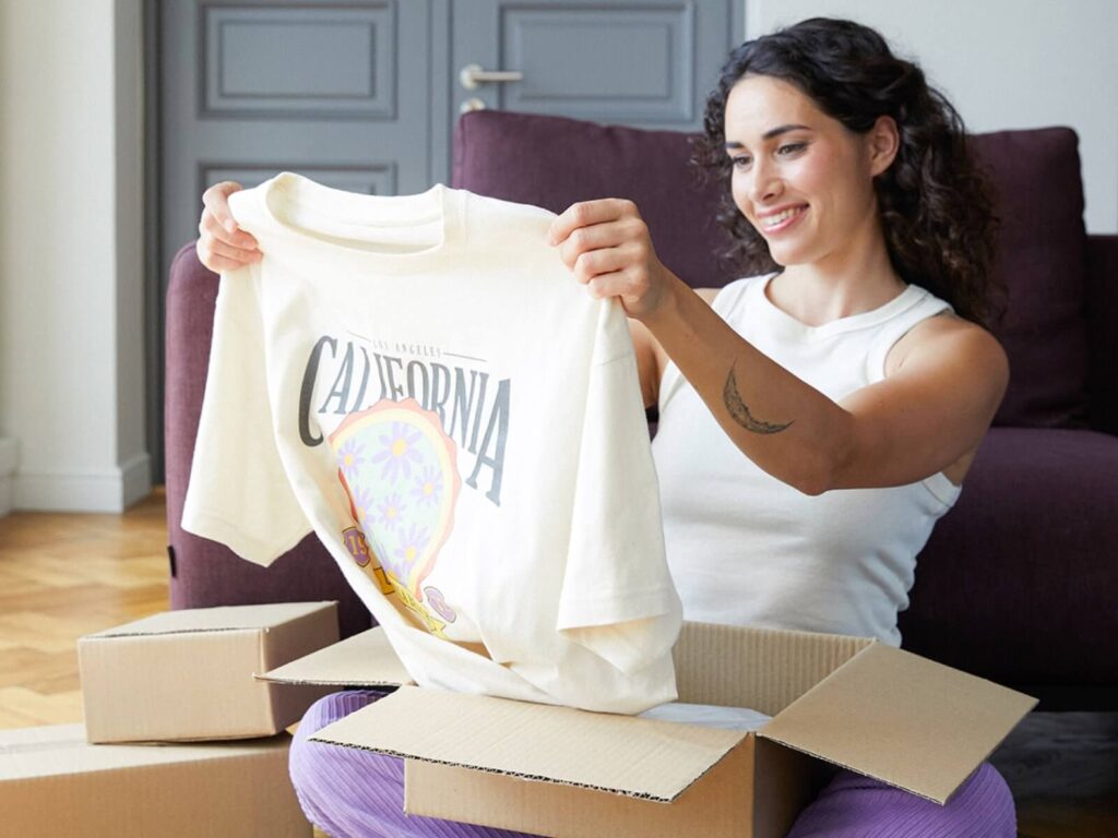 A woman looking at a t-shirt she just unpacked.