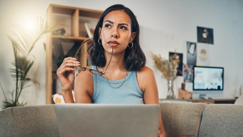 A woman working on a laptop and thinking.