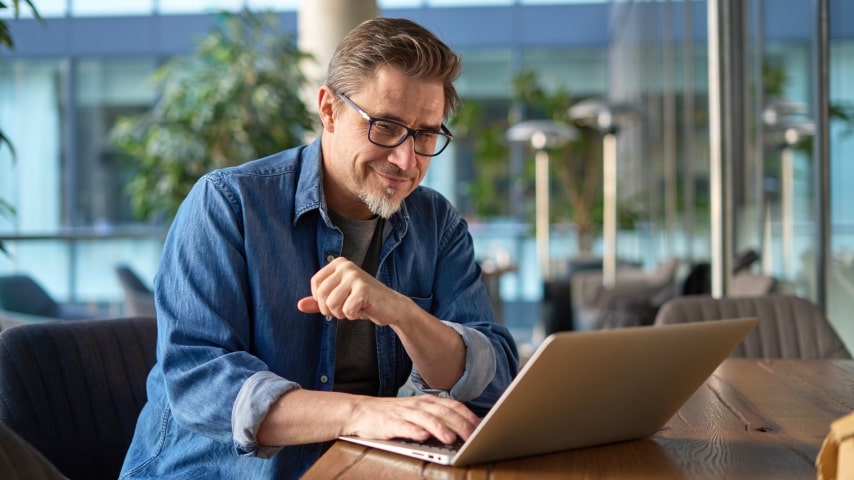 A man looking at a laptop screen and smiling.