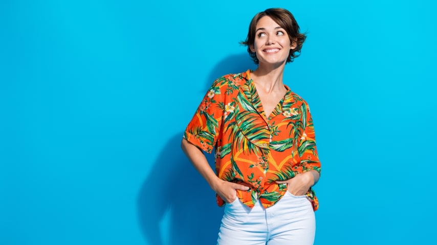 What Makes Printify the Best Sublimation Printing Provider A woman wearing a colorful orange AOP shirt with a pattern of leaves and flowers.