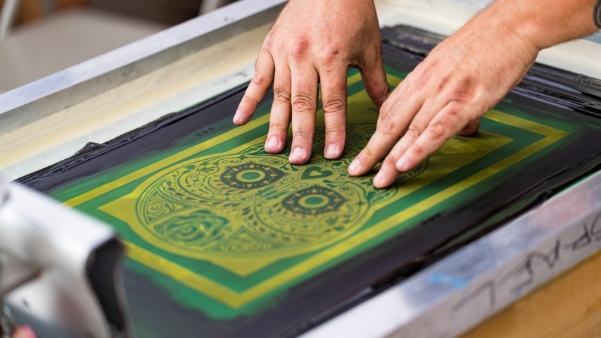 Where Is Screen Printing Used A person using screen printing equipment to make a custom t-shirt.