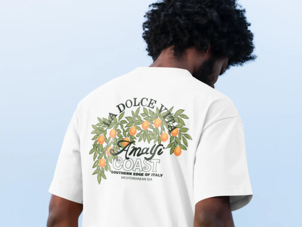 Man wearing a white t-shirt with a design of orange branches and leaves. Text reads "La Dolce Vita, Amalfi Coast”.