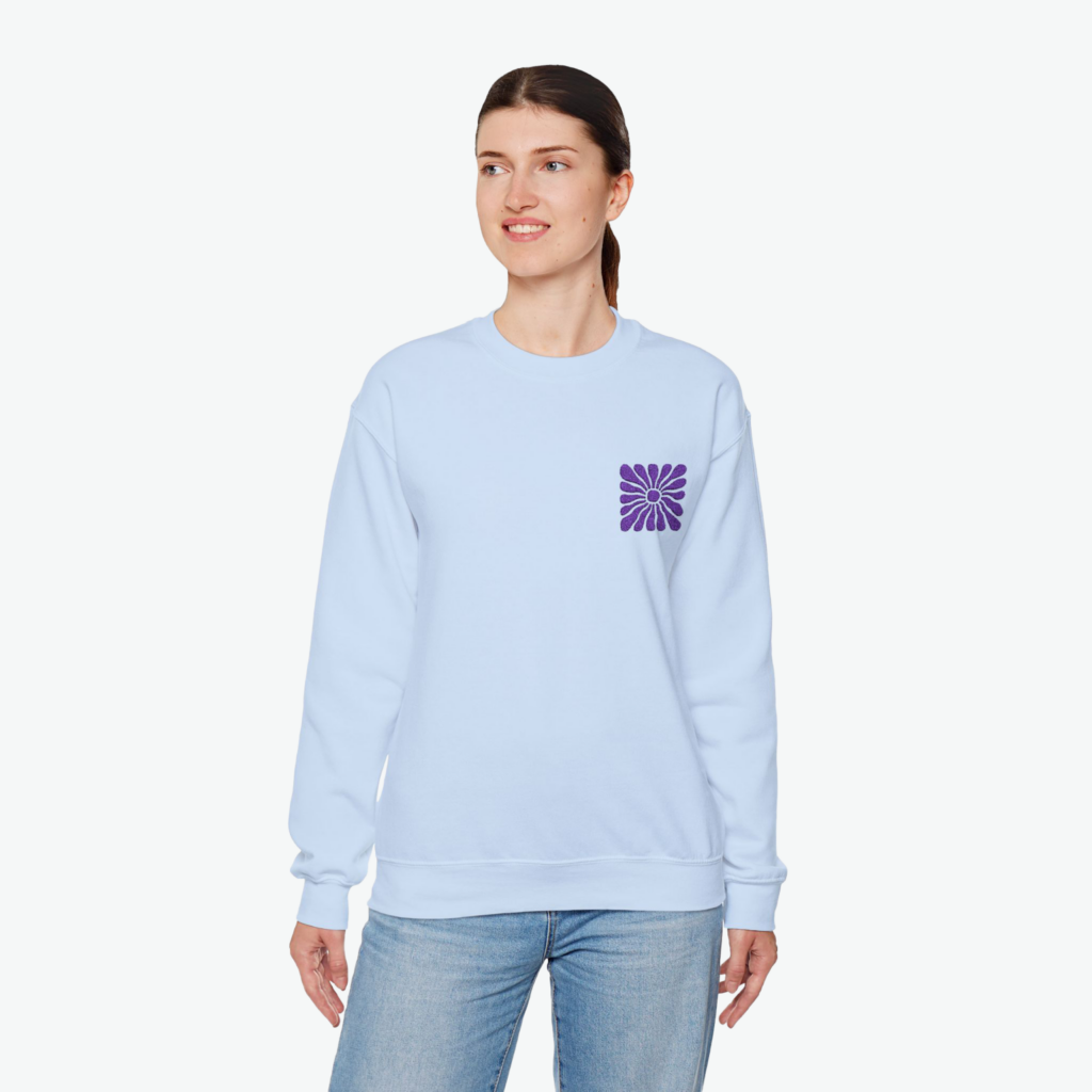 A woman wearing a light blue hoodie with a small abstract shape print against a white background.