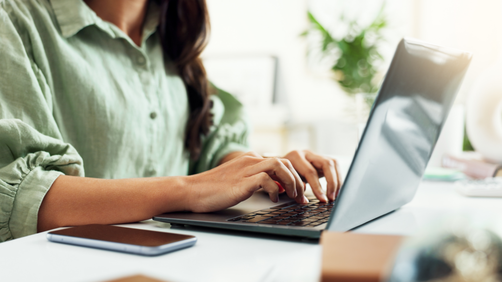 Cassini and eBay listings A woman in a green blouse sitting at a desk and using a laptop.