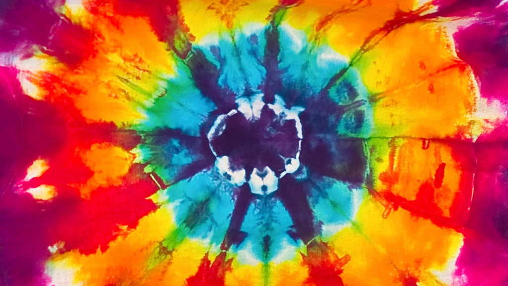Going psychedelic 4 Trippy cool tie dye patterns A vibrant tie-dye pattern with a central burst of blue and white, surrounded by rings of red, orange, yellow, and green.