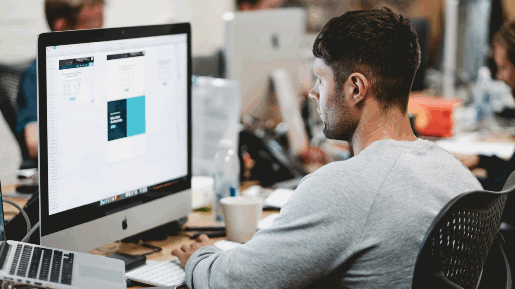 Prepare your t shirt design file A man is doing graphic design work on a large monitor.