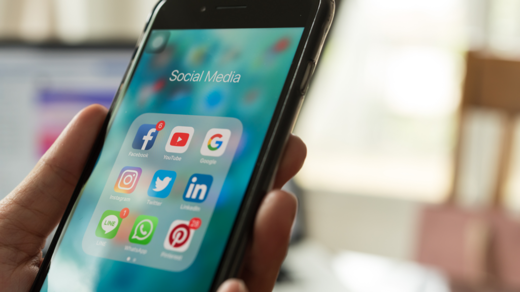 Use social media A person holding a mobile phone with various social media app icons on display.