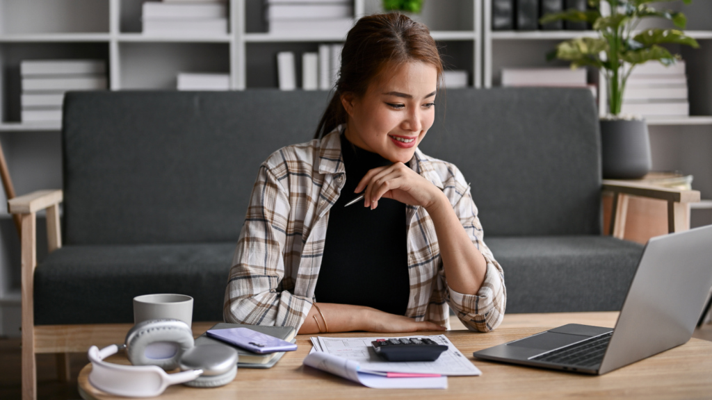 What to consider before setting a price A woman sitting at a table, working on a laptop with a cup of coffee beside her.