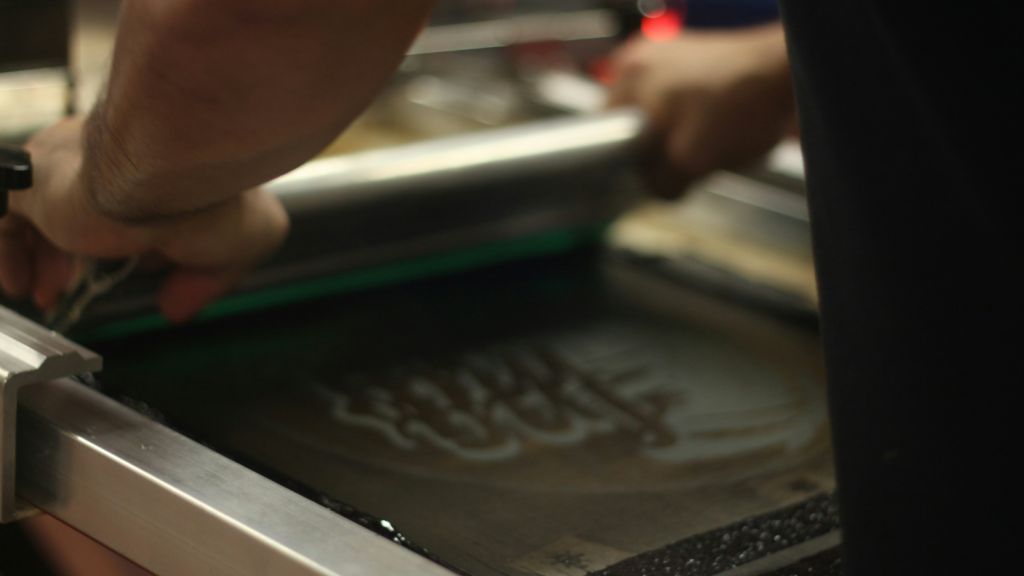 Whats the difference between DTF and screen printing A person using screen printing to create a custom t-shirt.