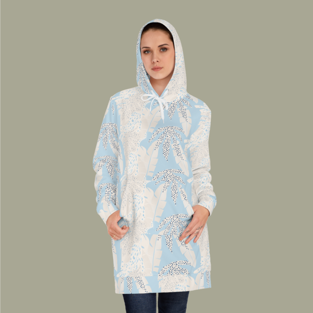 A woman in a custom white hoodie dress with an abstract floral print against a light gray background.